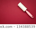 Cloth fabrics cleaner lint roller brush with paper roll on red background. Sticky roller, pet cat dog fur dust hair remover 134388539