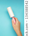 Woman holding lint roller on blue background. Vertical photo 134388542