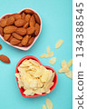 Fresh almond flakes and nuts in bowl on blue background. Vertical photo 134388545