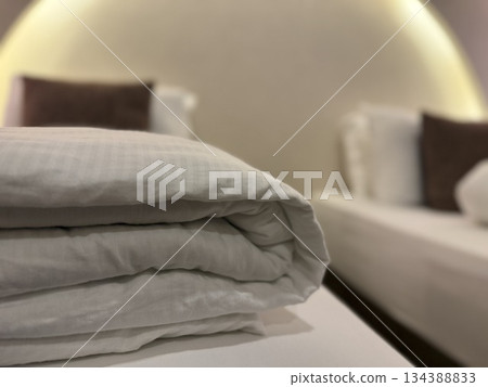 Folded bed linen on soft focus hotel bed background in cozy room ambiance Folded bed linen on soft focus hotel bed background in cozy room ambiance 134388833