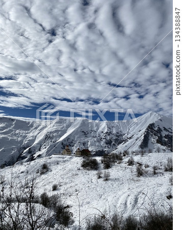Snow-covered mountain landscape with cloudy sky, perfect for winter backgrounds and nature themes 134388847