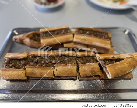 Turkish pide with minced meat served on a silver tray for a cultural dining experience Turkish pide with minced meat served on a silver tray for a cultural dining experience 134388853