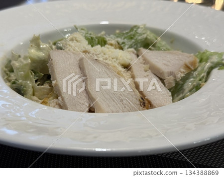 Caesar salad with grilled chicken and parmesan on elegant white plate 134388869