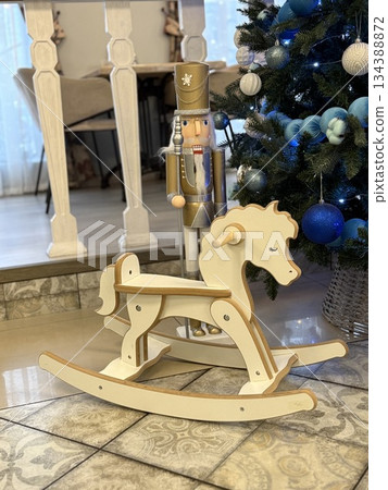 Christmas nutcracker soldier near decorated tree and wooden rocking horse in festive room 134388872