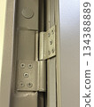 Metal hinge of a gray door with detailed screws and texture, suitable as industrial background Metal hinge of a gray door with detailed screws and texture, suitable as industrial background 134388889