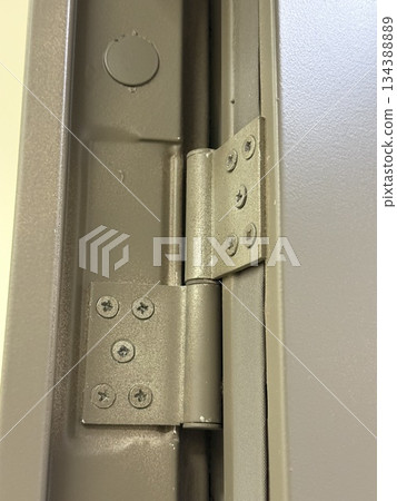 Metal hinge of a gray door with detailed screws and texture, suitable as industrial background Metal hinge of a gray door with detailed screws and texture, suitable as industrial background 134388889