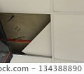 Unfinished office ceiling with missing tile and visible red pipe, wires and textured background Unfinished office ceiling with missing tile and visible red pipe, wires and textured background 134388890