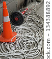 Traffic cone and tangled cables on concrete pavement, urban maintenance and safety concept Traffic cone and tangled cables on concrete pavement, urban maintenance and safety concept 134388892