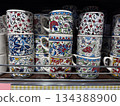 Colorful ceramic mugs with intricate floral patterns stacked on shelf display Colorful ceramic mugs with intricate floral patterns stacked on shelf display 134388900