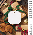 Blank paper gift tag on wrapped Christmas present near rustic wooden decor, holiday mockup 134389411