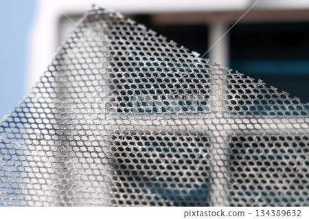 Dusty dirty mesh filter against background of air purifier panel. Maintenance of household appliances 134389632