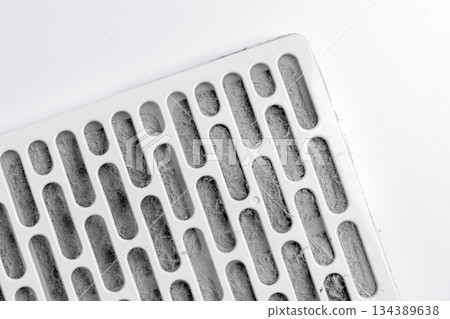 Air filter covered with thick layer of dust under plastic grille on white table surface Air filter covered with thick layer of dust under plastic grille on white table surface 134389638