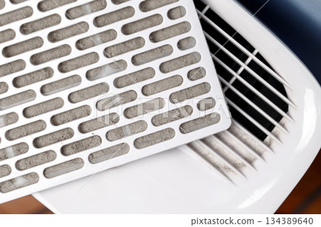 Dust clogged air filter cartridge on home dehumidifier panel. Technical maintenance concept Dust clogged air filter cartridge on home dehumidifier panel. Technical maintenance concept 134389640