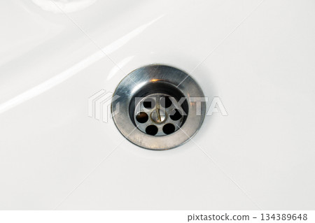 Clean metal drain in white sink surface. Household maintenance concept 134389648