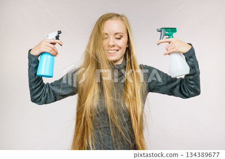 Female messy long hair holds spray bottle Female messy long hair holds spray bottle 134389677