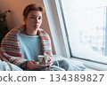 young woman warms up with hot tea in winter weather at home 134389827