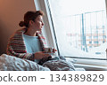 young woman warms up with hot tea in winter weather at home 134389829