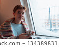 young woman warms up with hot tea in winter weather at home 134389831