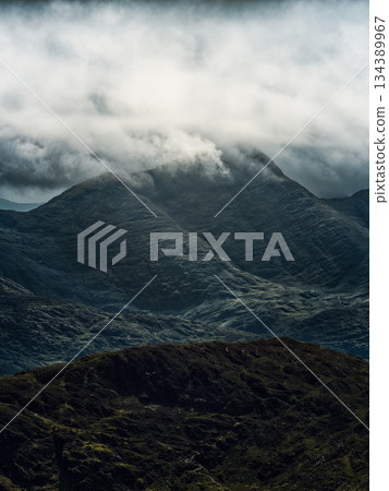 Striking vertical composition showcasing rugged mountains, where muted tones and cloudy skies create a sense of depth and ethereal beauty. Majestic nature! 134389967