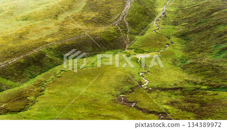 Streams and paths crisscross a green grassy landscape. The area is likely for hiking and is located within the Coomloughra Horseshoe region. Streams and paths crisscross a green grassy landscape. The area is likely for hiking and is located within the Coomloughra Horseshoe region. 134389972