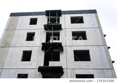 Concrete apartment building under construction with facade openings and balcony platforms installed 134391086