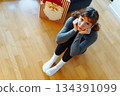 young woman with curly hair sits on floor near bag of Christmas gifts 134391099