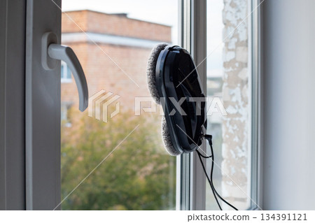 Window cleaning robot cleans the inside of a city apartment window. Modern household cleaning appliances. 134391121