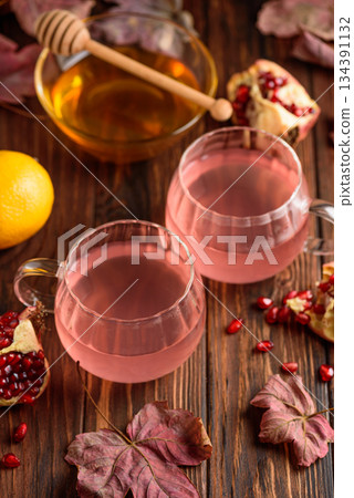 Autumn Beverage: two Cups ofPomegranate Tea with Lemon and Ginger on Rustic Table 134391132