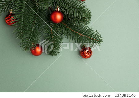 Red Christmas Ornaments Hanging on Pine Branches over Muted Green Background 134391146