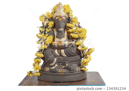 Ganesha idol decoration with gold colored coating and yellow marigold garland for Hindu rituals 134391234