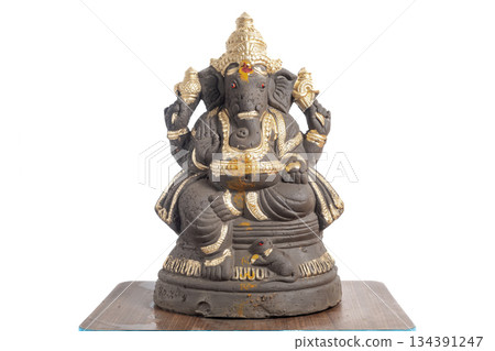 Clay Ganesha idol decorated in gold color for home decoration and spiritual worship. 134391247