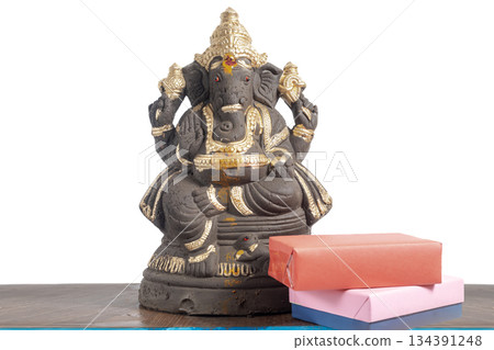 Clay Ganesha idol with gift box on a wooden table 134391248