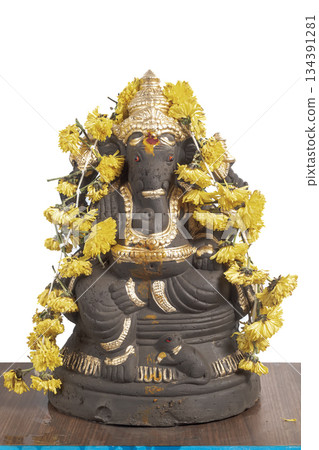 Ganesha idol decoration with gold colored coating and yellow marigold garland for Hindu rituals 134391281