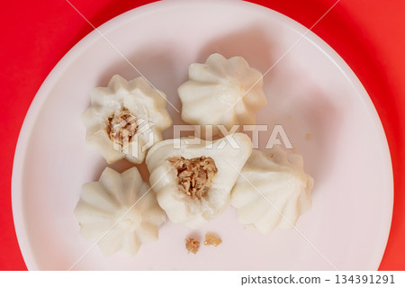 Steamed sweet modak rice dumplings on a white plate against a bright red background Steamed sweet modak rice dumplings on a white plate against a bright red background 134391291
