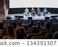 Panel discussion at a conference stage with audience listening to speakers during a business seminar 134391307