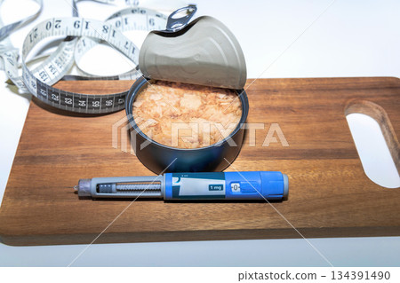 Weight loss concept featuring tuna fish and ozempic pen. Weight loss concept featuring tuna fish and ozempic pen. 134391490