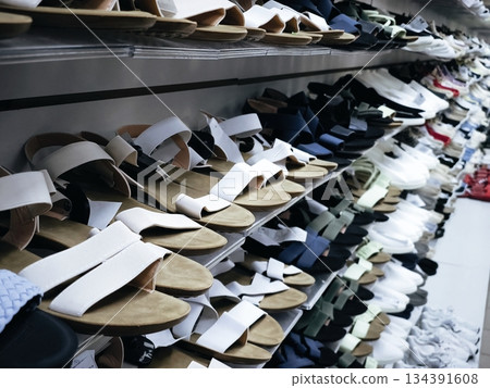 Summer Sandals Display in Shoe Store. Variety of fashionable summer sandals neatly arranged on shelves in a shoe store, featuring white, beige and colorful designs for seasonal shopping. 134391608