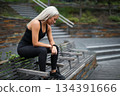 Athletic woman resting on a bench in a serene urban setting 134391666