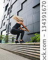 Woman performing exercises during outdoor workout near a modern urban building 134391670