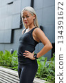 Confident woman in activewear standing outdoors near urban architecture 134391672