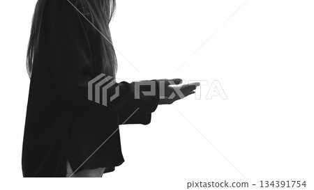 Unrecognizable woman worship God praying raising her hands while standing on a white background. Serene atmosphere of faith and spiritual connection, gratitude and praise. Copy space. Black and white. 134391754