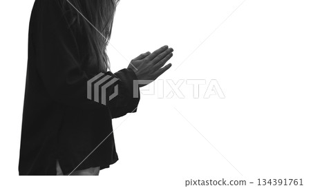 An unrecognizable woman, prays with clasped hands for help, standing on white background. A serene atmosphere of faith and spiritual connection, worship and praise, hope. Copy space. Black and white. 134391761