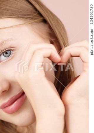 A smiliing girl forms a heart shape hands. Self care ads. Face. Love Support. Caring Positive. Gen Alpha. Natural beauty. Glowing skin. Youthful confidence. Individuality. Real beauty. Self-expression 134391789