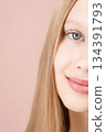 Half face. Portrait of a funny smiling young girl. Blonde Caucasian with blue eyes isolated on pink background. Advertising concept skin care for teenagers. Hair care. Copy space. Self care Gen Alpha 134391793