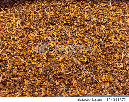 Crushed chili spice blend with seeds spread densely across a display tray. Spicy cuisine, bold flavor profiles, and traditional seasoning culture expressed through texture and contrast. 134391872