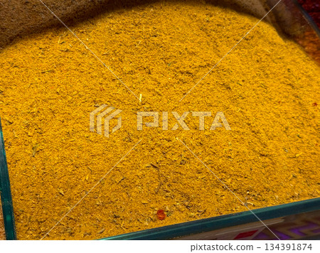 Ground turmeric powder forming a smooth golden surface inside a spice container in Istanbul bazaar. Traditional seasoning, natural color, and culinary heritage emphasized through fine texture and 134391874