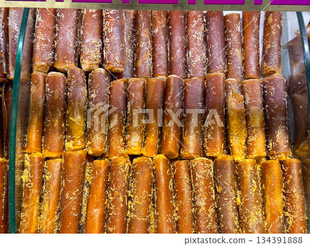 Rolled fruit leather sheets aligned in rows inside a market display case in Istanbul bazaar. Traditional preservation methods, natural sweetness, and simple ingredients reflecting culinary heritage Rolled fruit leather sheets aligned in rows inside a market display case in Istanbul bazaar. Traditional preservation methods, natural sweetness, and simple ingredients reflecting culinary heritage 134391888