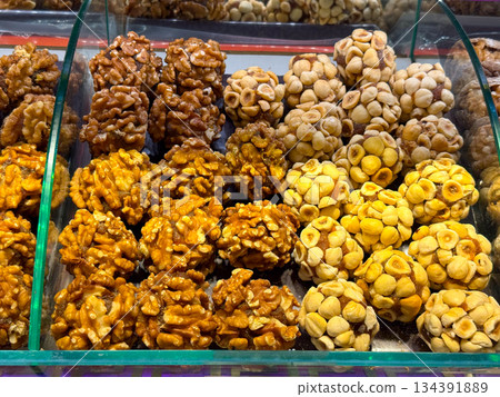 Nut and fruit based sweets arranged in compact clusters inside a display case in Istanbul bazaar. Traditional confectionery, natural energy foods, and artisanal craftsmanship presented through texture Nut and fruit based sweets arranged in compact clusters inside a display case in Istanbul bazaar. Traditional confectionery, natural energy foods, and artisanal craftsmanship presented through texture 134391889