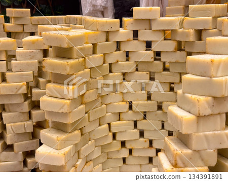Neutral toned soap bars stacked in layered rows forming a textured wall display. Minimalist skincare, handmade production, and orderly presentation highlighting purity, routine, and everyday self care 134391891