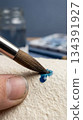 Paintbrush applying blue watercolor paint detail 134391927